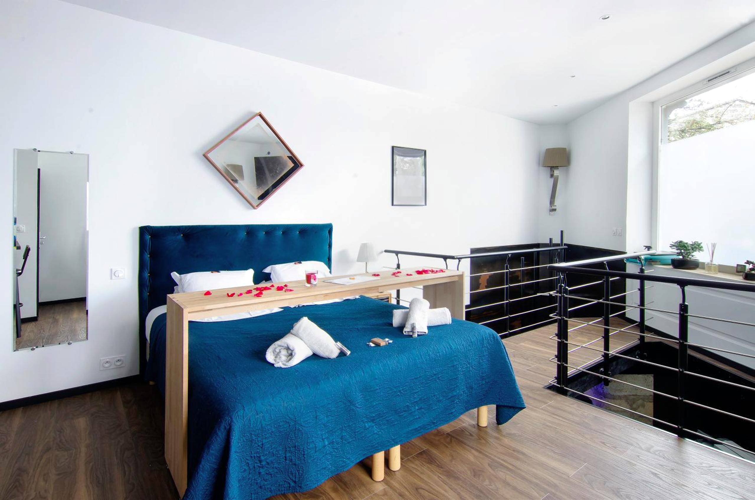 Lit double avec jeté bleu et pétales de rose - Mieuxqualhotel jacuzzi privatif La retro