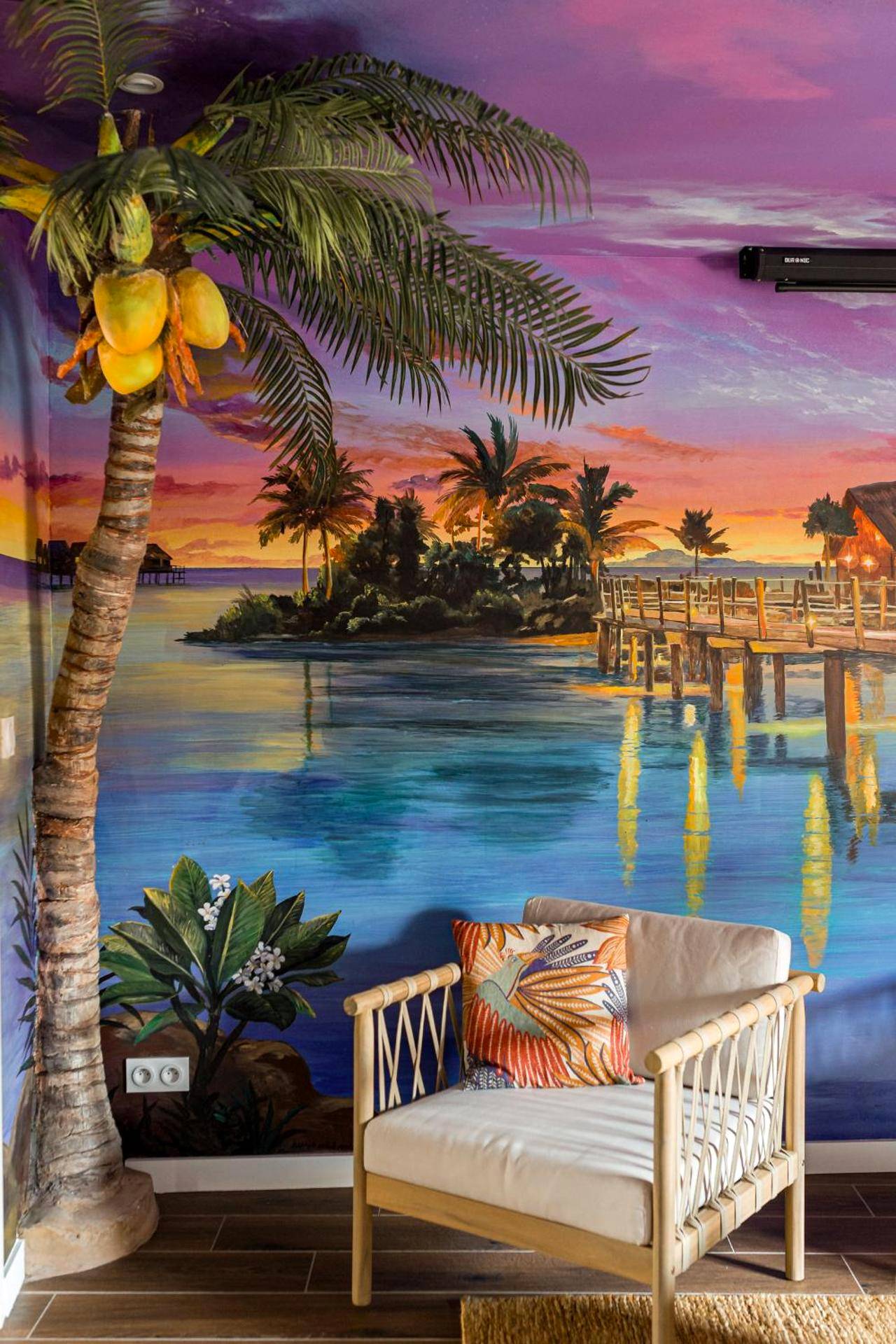 Fauteuil en bois devant une fresque de lagon - Moments de douceur - Suite Laponie et Suite Tahiti