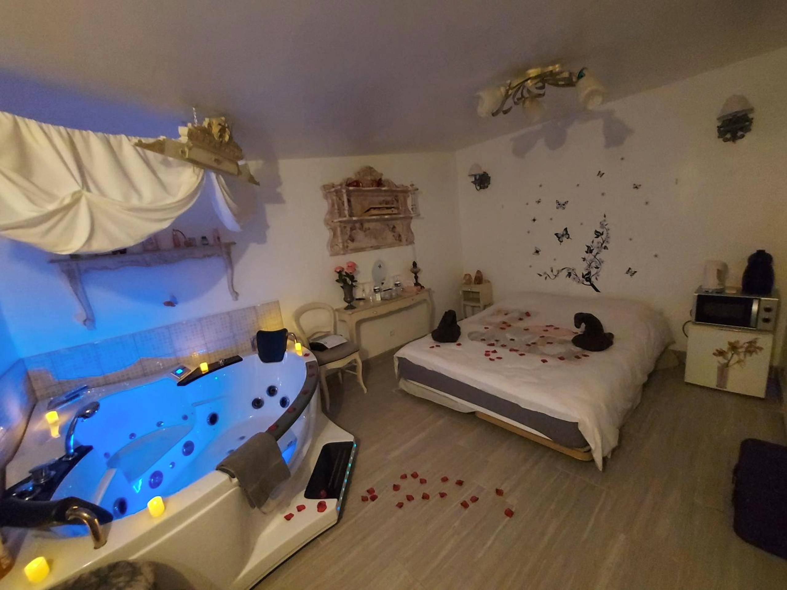 Jacuzzi lumineux bleu et lit avec pétales - Mon Désir