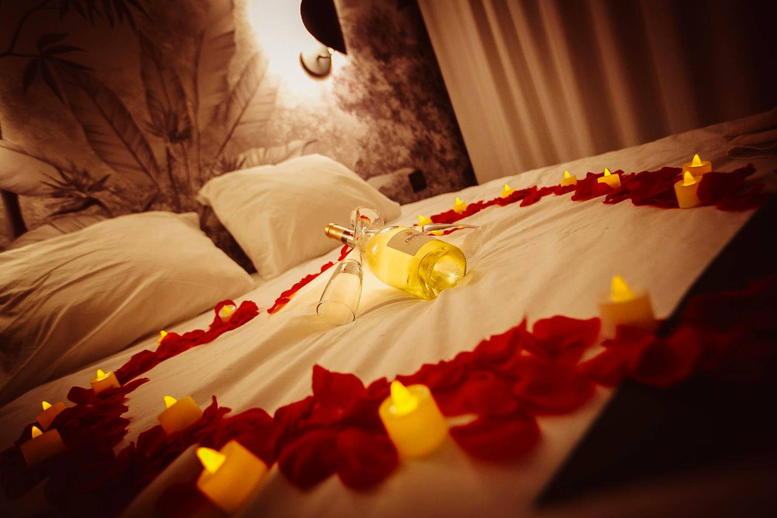 Lit décoré de pétales de rose et bougies - Love Room du Mont d'Or - Baignoire SPA - Minibar offert