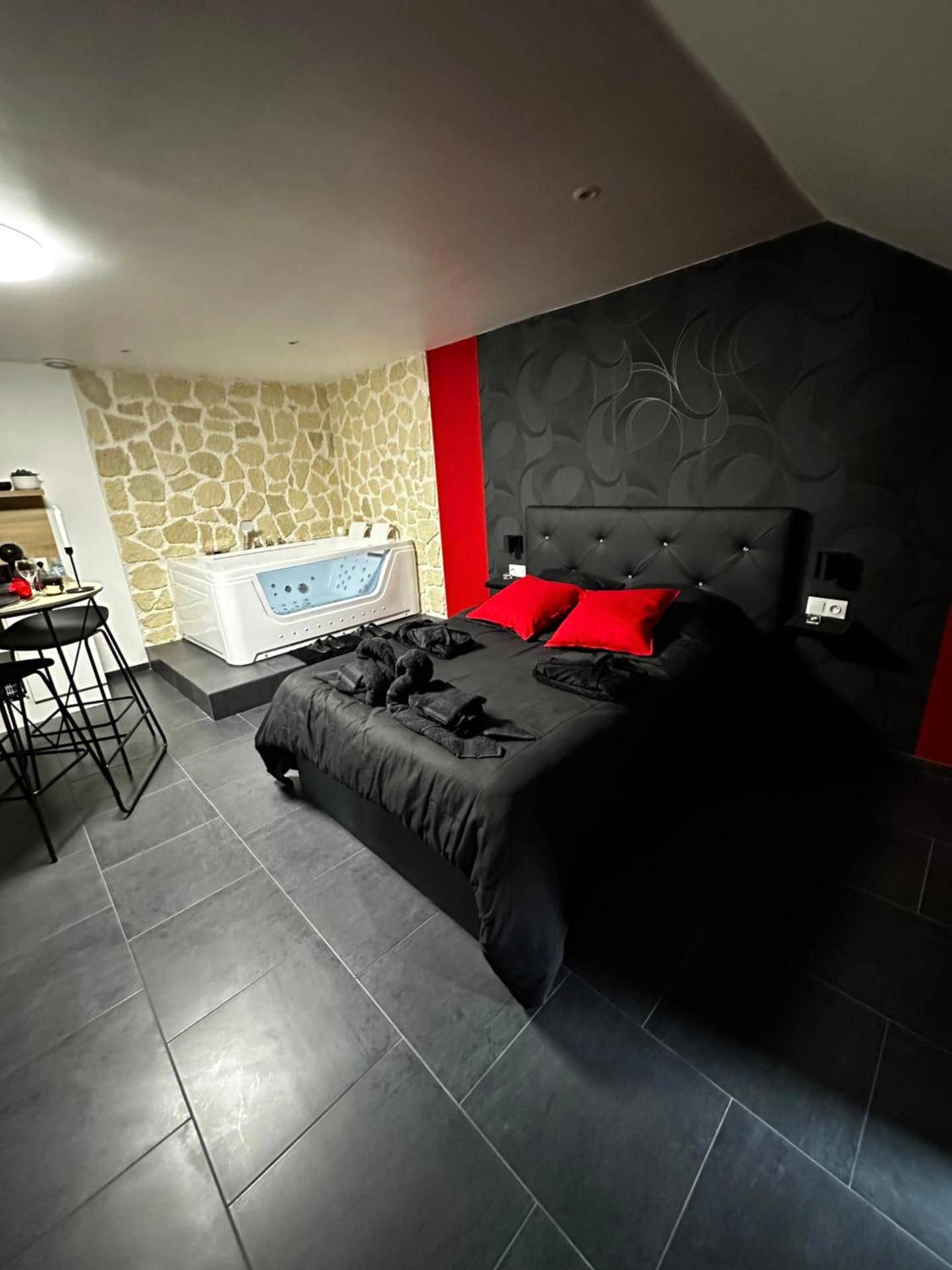 Lit king size et jacuzzi devant mur en pierre - Msroom