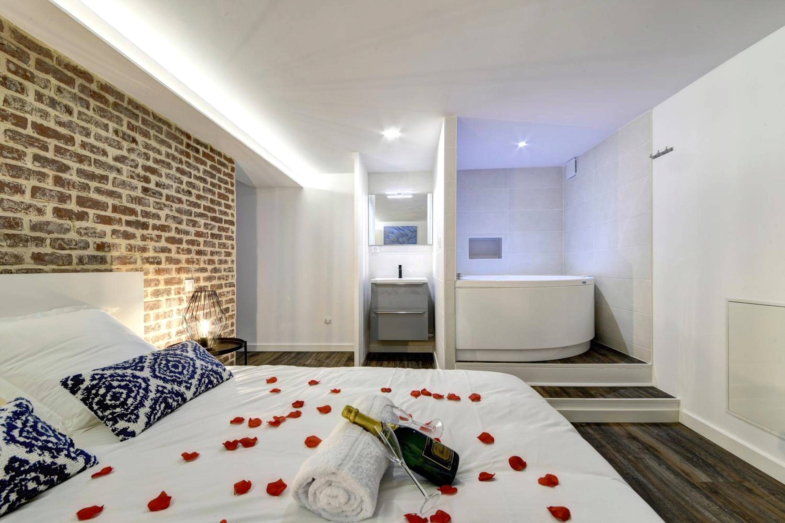 Lit avec pétales de rose et jacuzzi en fond - Love Room Toulouse - My Toul'House SPA