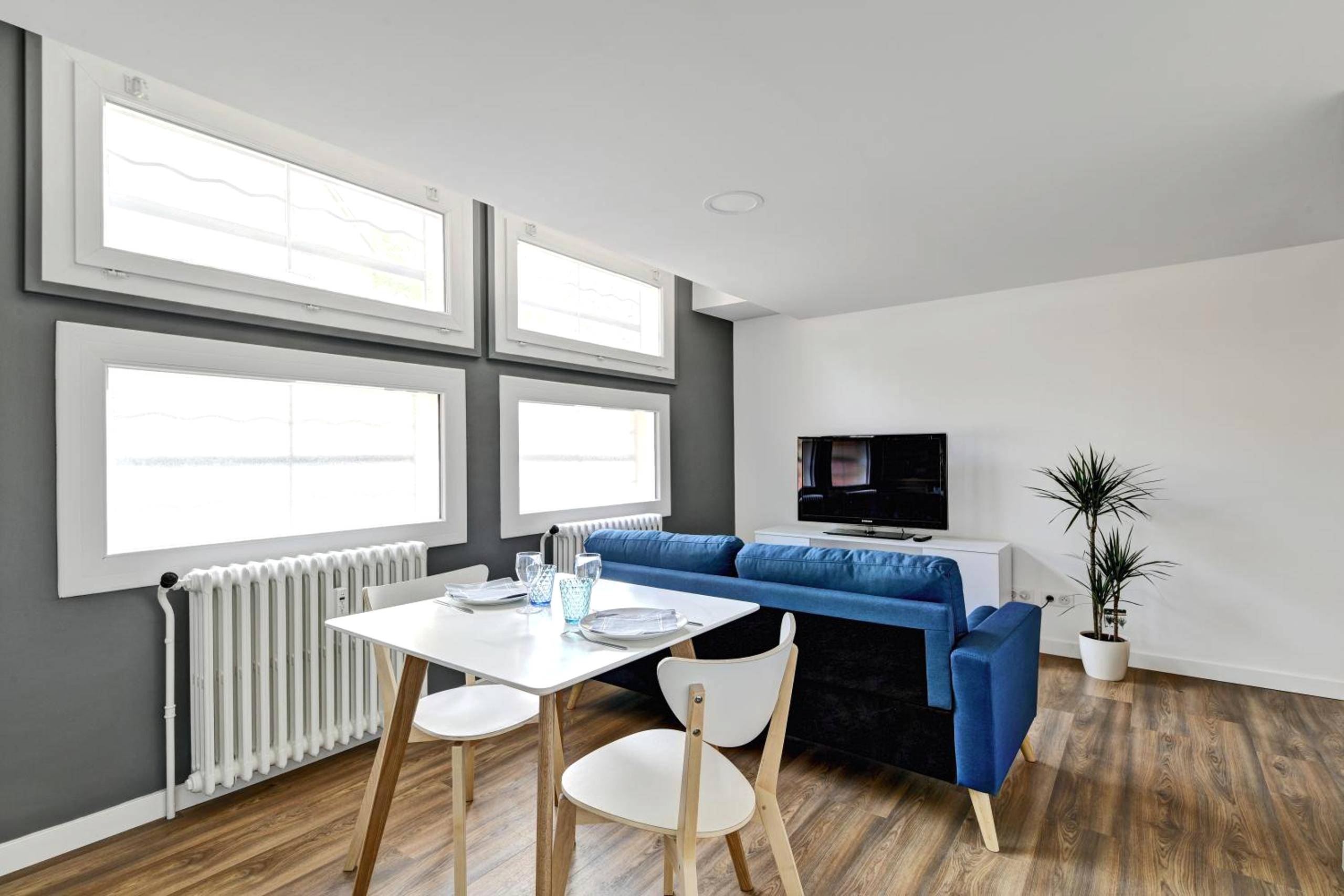 Espace repas avec table blanche et canapé bleu - My Toul'House SPA