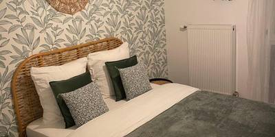 Chambre avec lit double et papier peint végétal - Nature&Spa Appartement avec Jacuzzi & Sauna privé