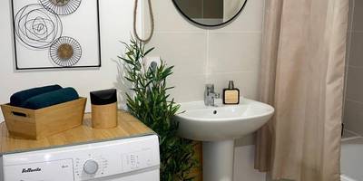 Salle de bain avec lave - linge et miroir rond - Nature&Spa Appartement avec Jacuzzi & Sauna privé