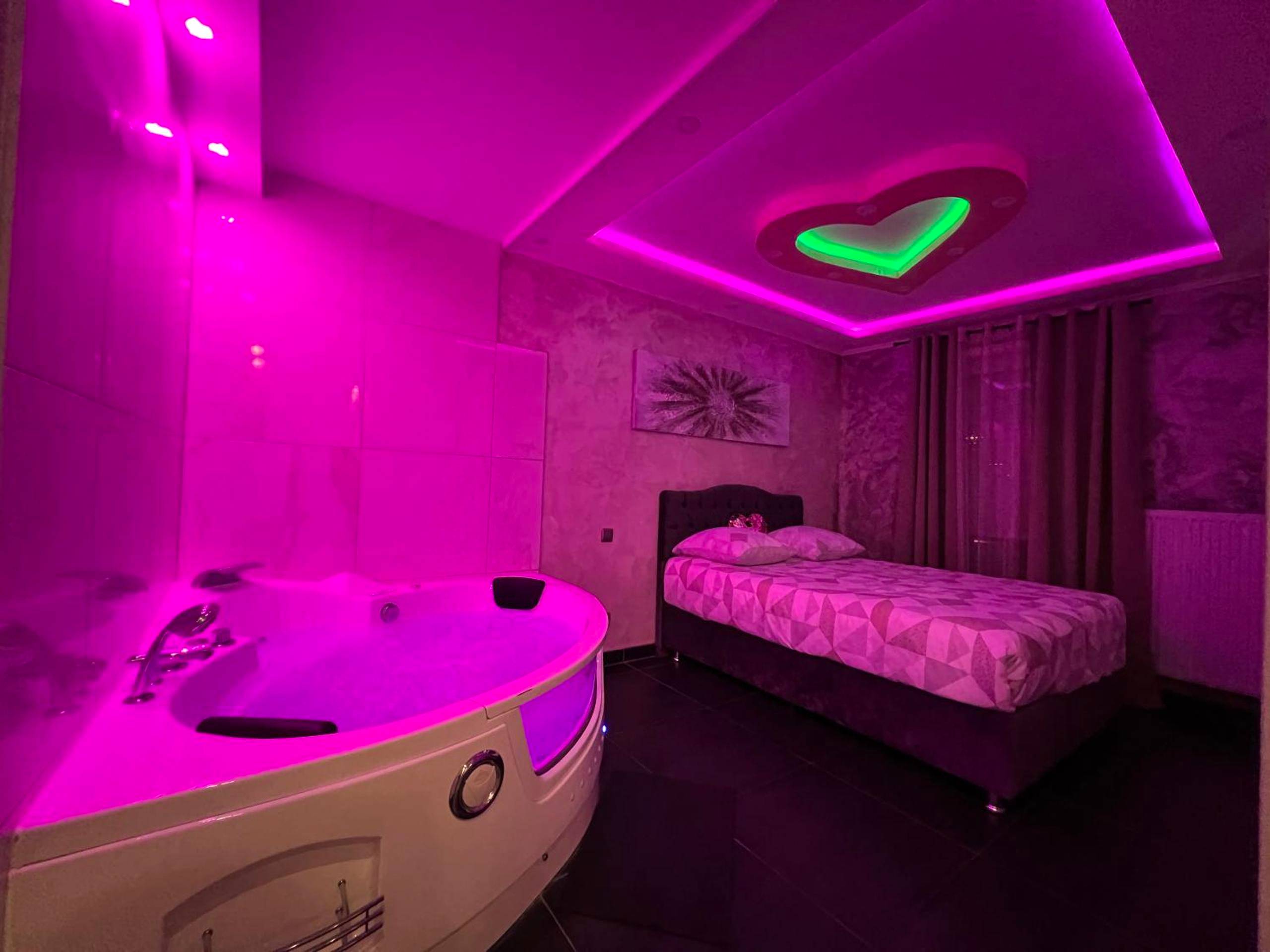 Jacuzzi et lit avec plafond cœur lumineux rose - Love Room Strasbourg - Nid d'Amour