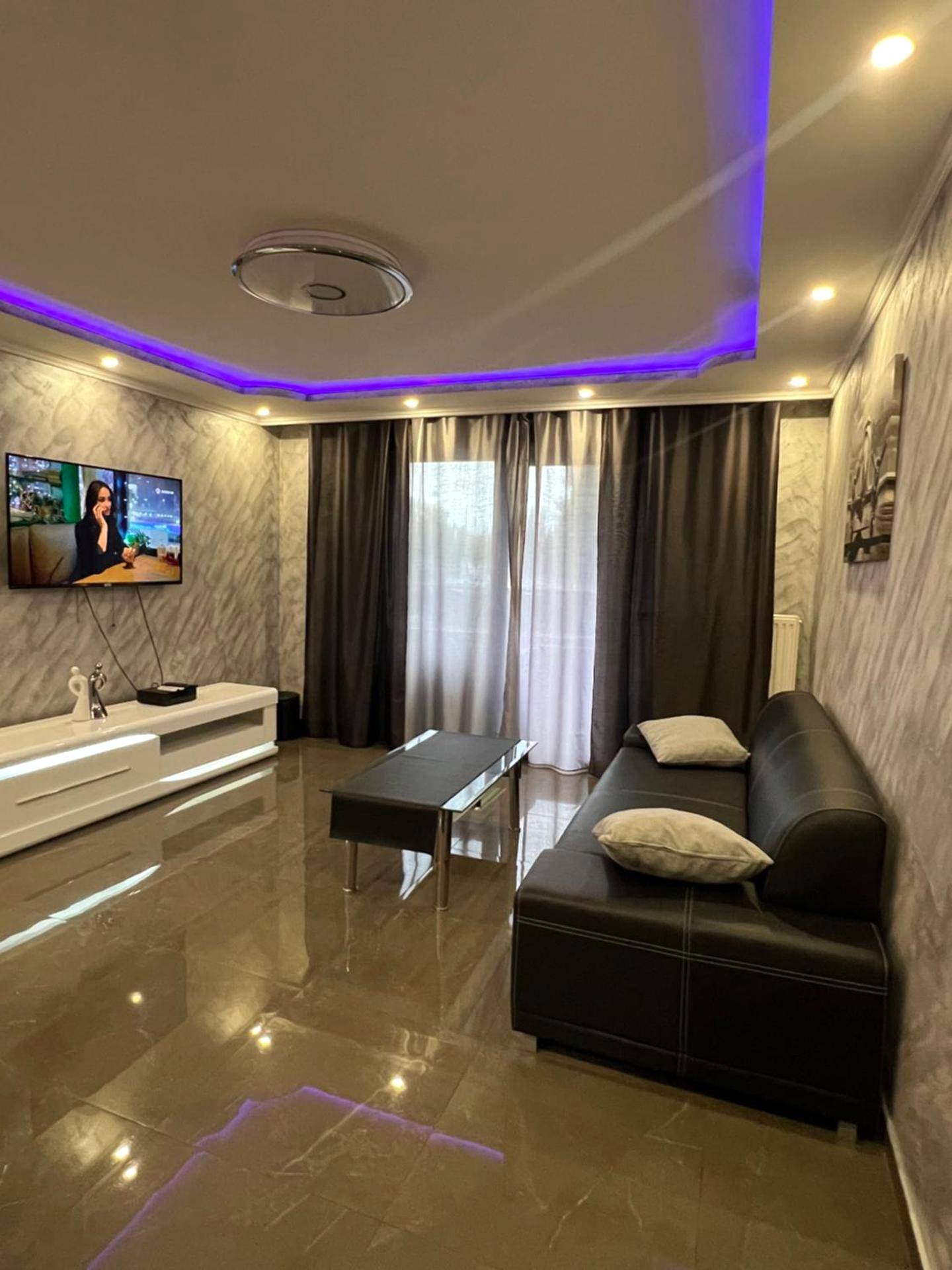 Salon avec canapé noir et télévision murale - Nid d'Amour