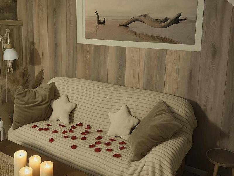 Canapé cosy avec pétales de roses et bougies - Gite au nid d'Ange