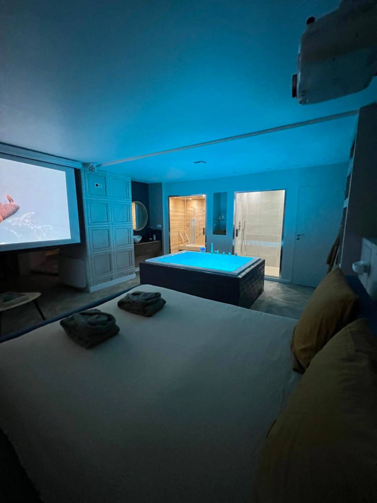 Espace nuit avec jacuzzi bleu et vidéoprojecteur - Appartement avec Jacuzzi Sauna & Home Cinéma - Nid d'Angers