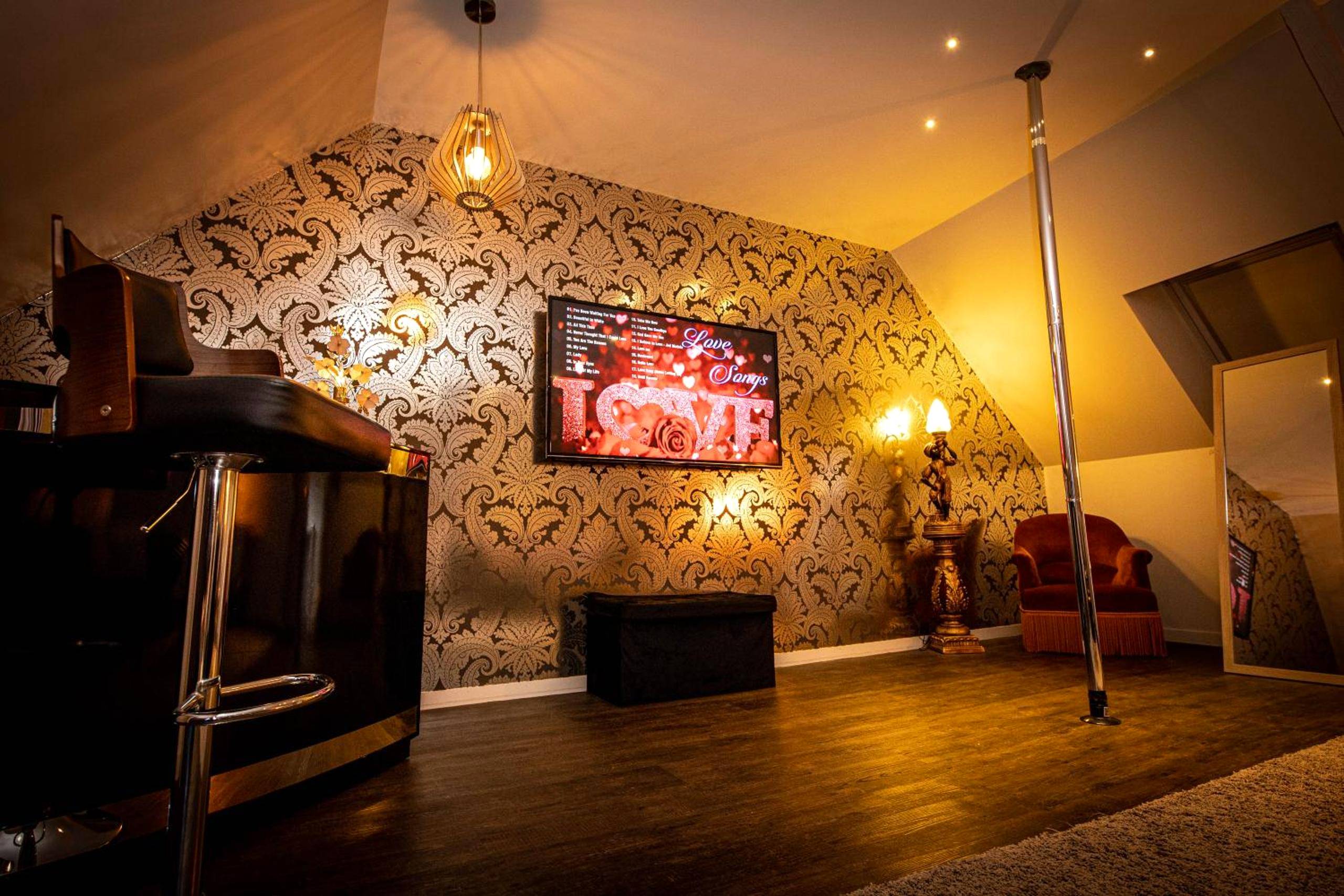 Espace détente avec barre de pole dance et TV - Nuances d'Alcôves