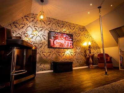Espace détente avec barre de pole dance et TV - Nuances d'Alcôves