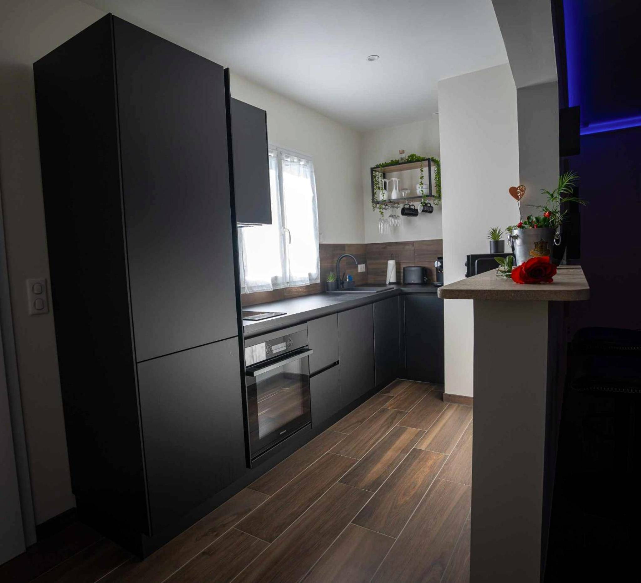 Cuisine équipée noire avec sol effet bois - LA NUIT DES SECRETS Love Room 4 étoiles avec Jacuzzi et Sauna