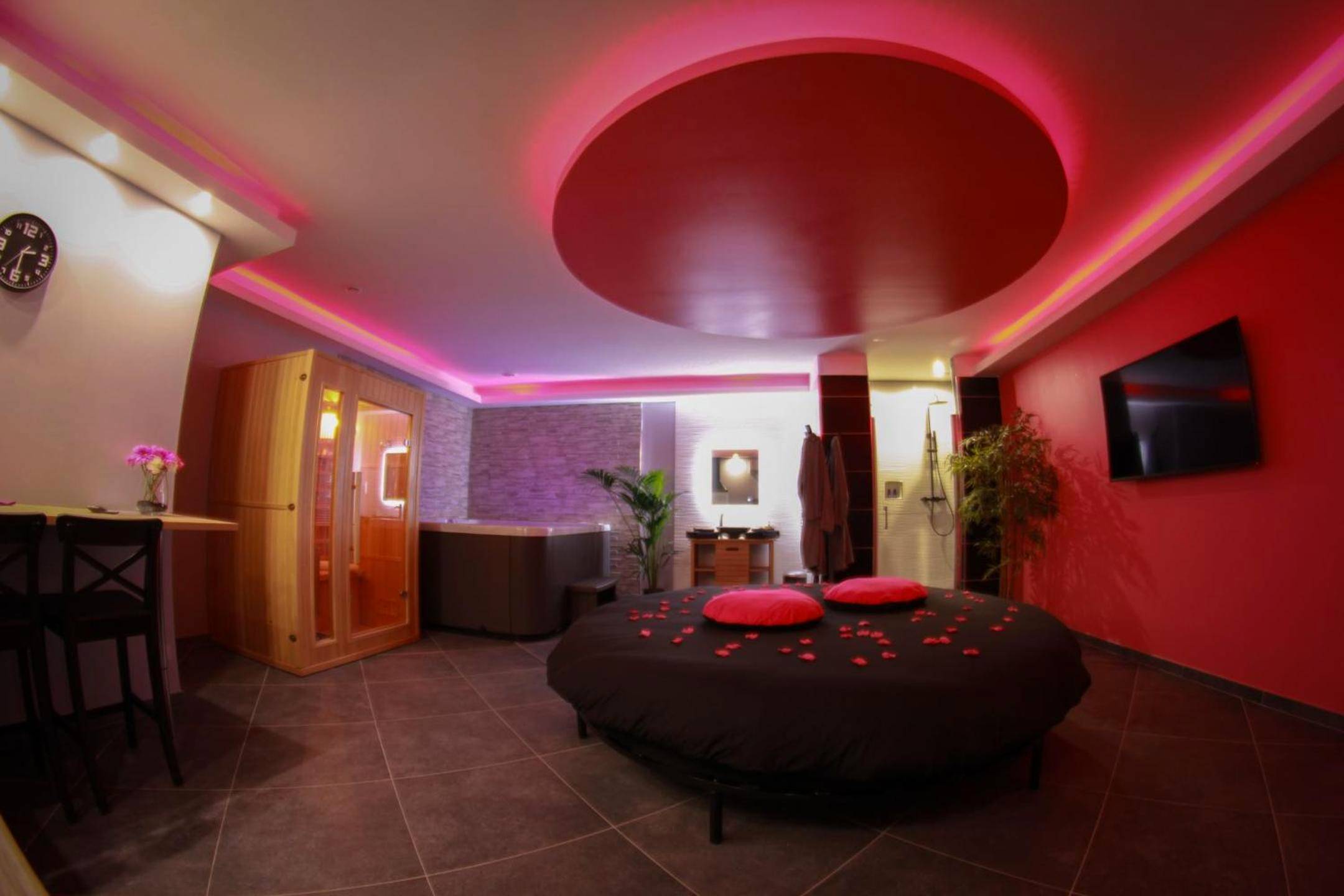 Lit rond avec pétales et sauna en arrière - plan - Love Room Le Rove - Nuit vip spa sauna privatif