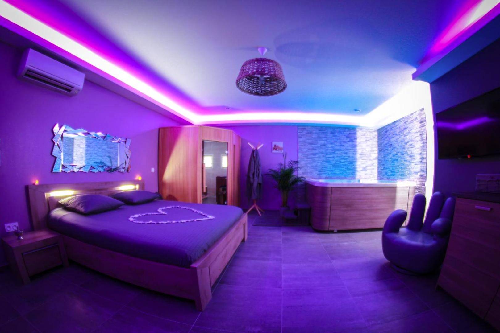 Vue d'ensemble de la suite avec néons violets - Nuit vip spa sauna privatif