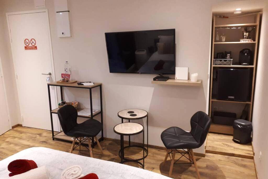 Espace salon avec TV murale et chaises design - SPA privatif Love room, Le Hammam et Bulles, chez Nuits Chartraines