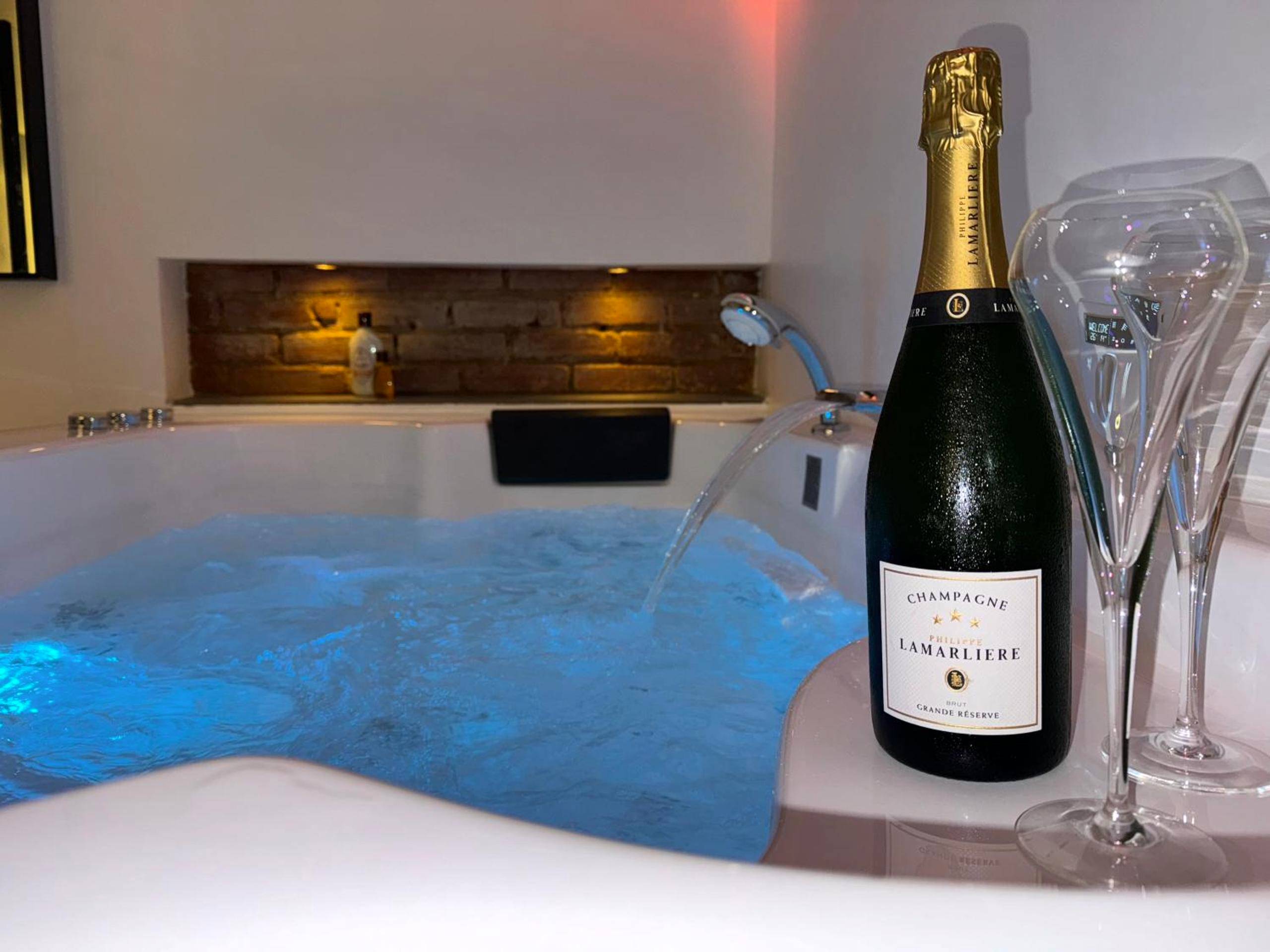 Bouteille de champagne devant le jacuzzi éclairé - Ô Roméo - Suite privée