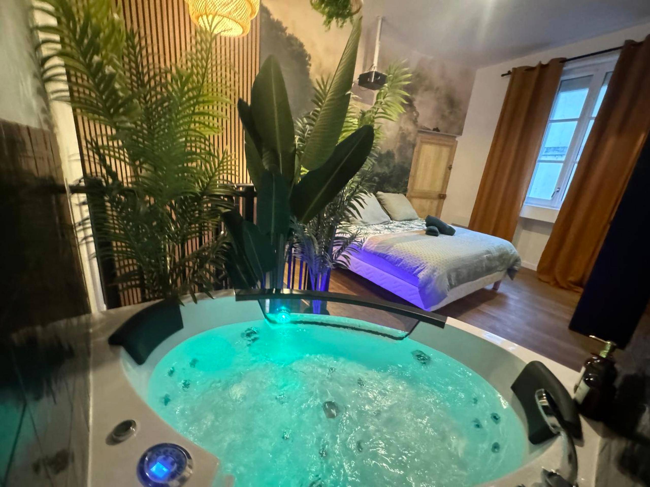 Jacuzzi privatif et lit double en arrière - plan - Love Room Angers - L'Oasis Angevine - Balneo, Sauna, Home Cinema & Parking