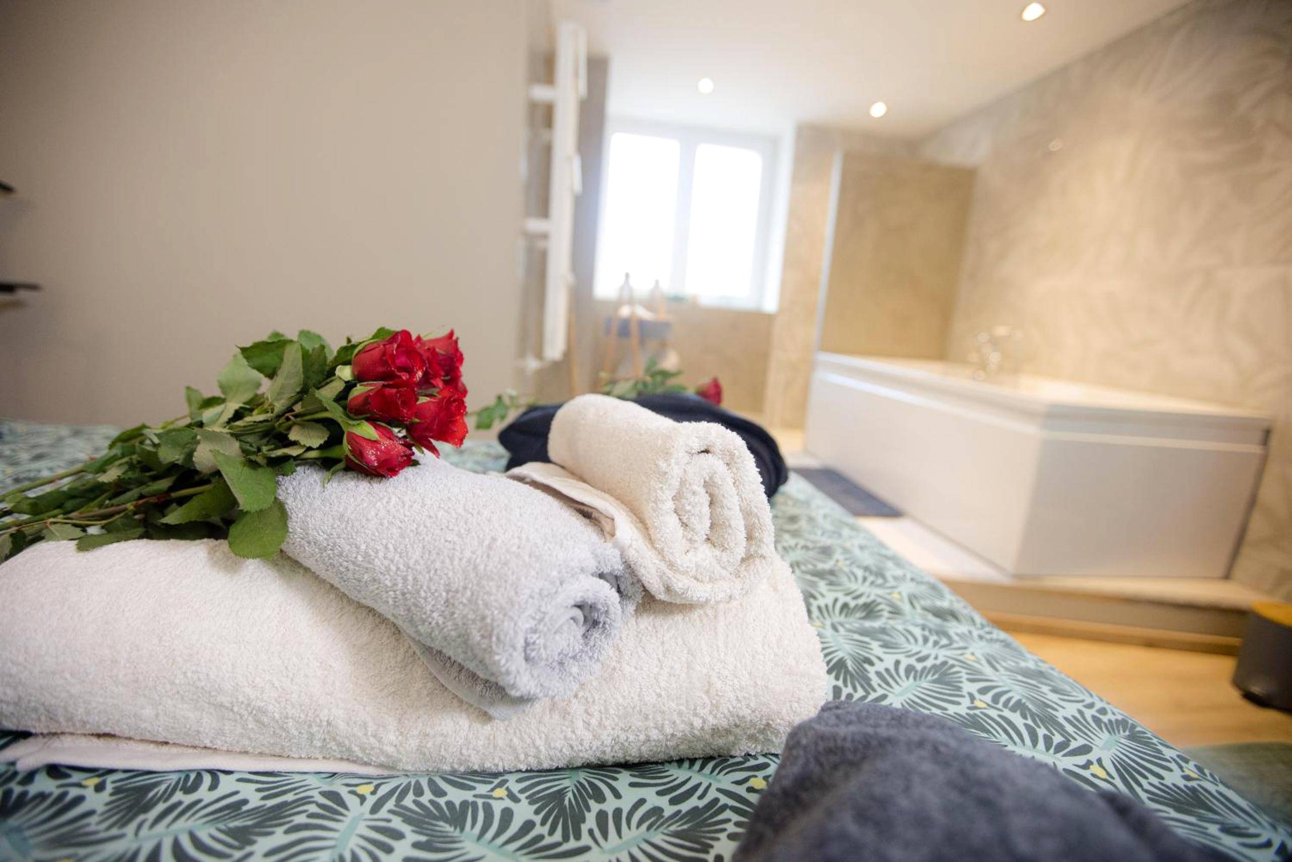 Serviettes et roses rouges sur le lit - ODYSSEE l'expérience commence ici JACUZZI