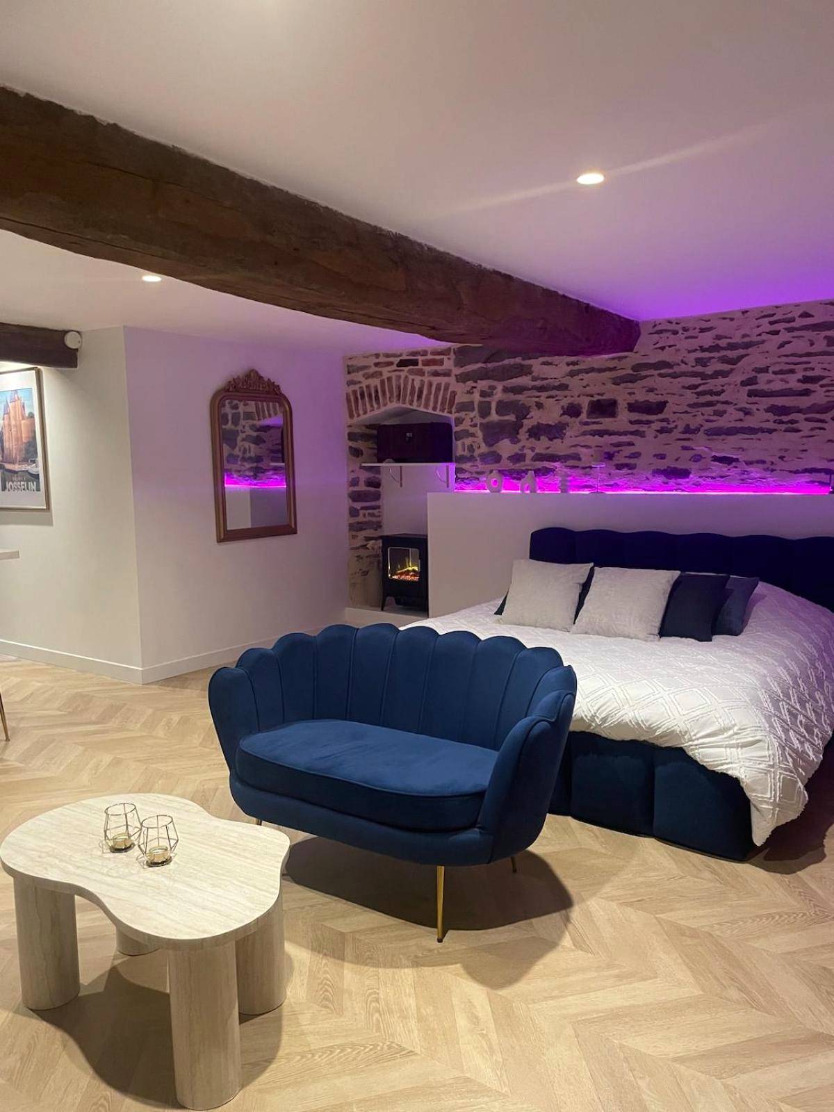 Chambre avec canapé bleu et mur en pierre - Ombre et Douceur