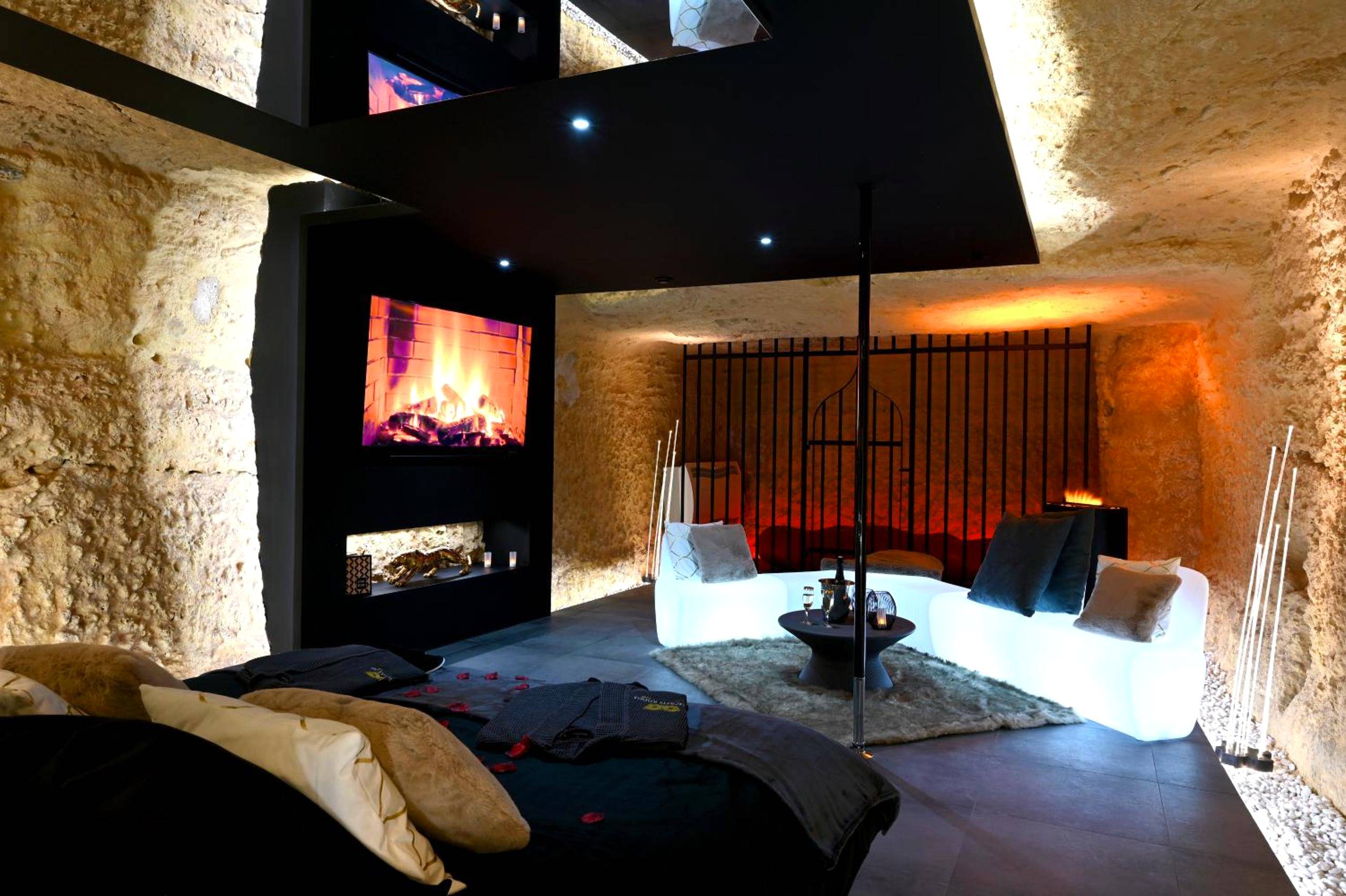 Salon avec canapé lumineux et écran cheminée - OMIRA - Nuits d'exception & spa