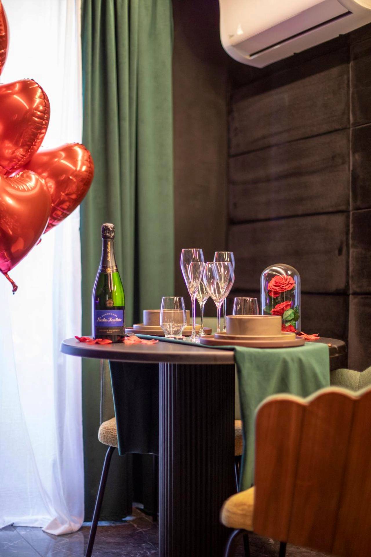 Table dressée avec champagne et ballons cœurs - One Night Love Room Unique