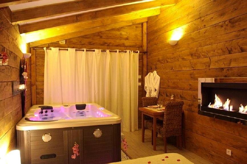 Jacuzzi et cheminée dans ambiance boisée - La Paillote Exotique Spa