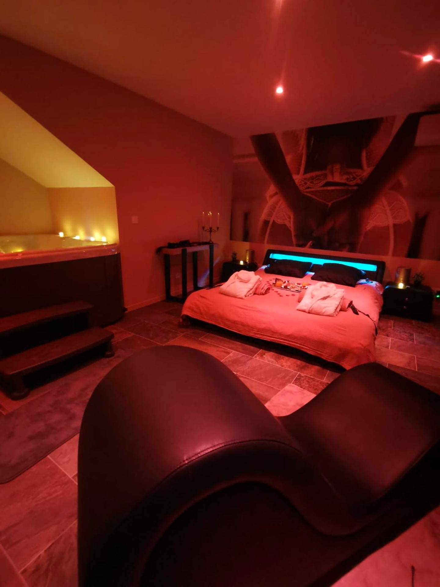 Lit king size et fauteuil tantrique sous néons - La parenthèse Love room