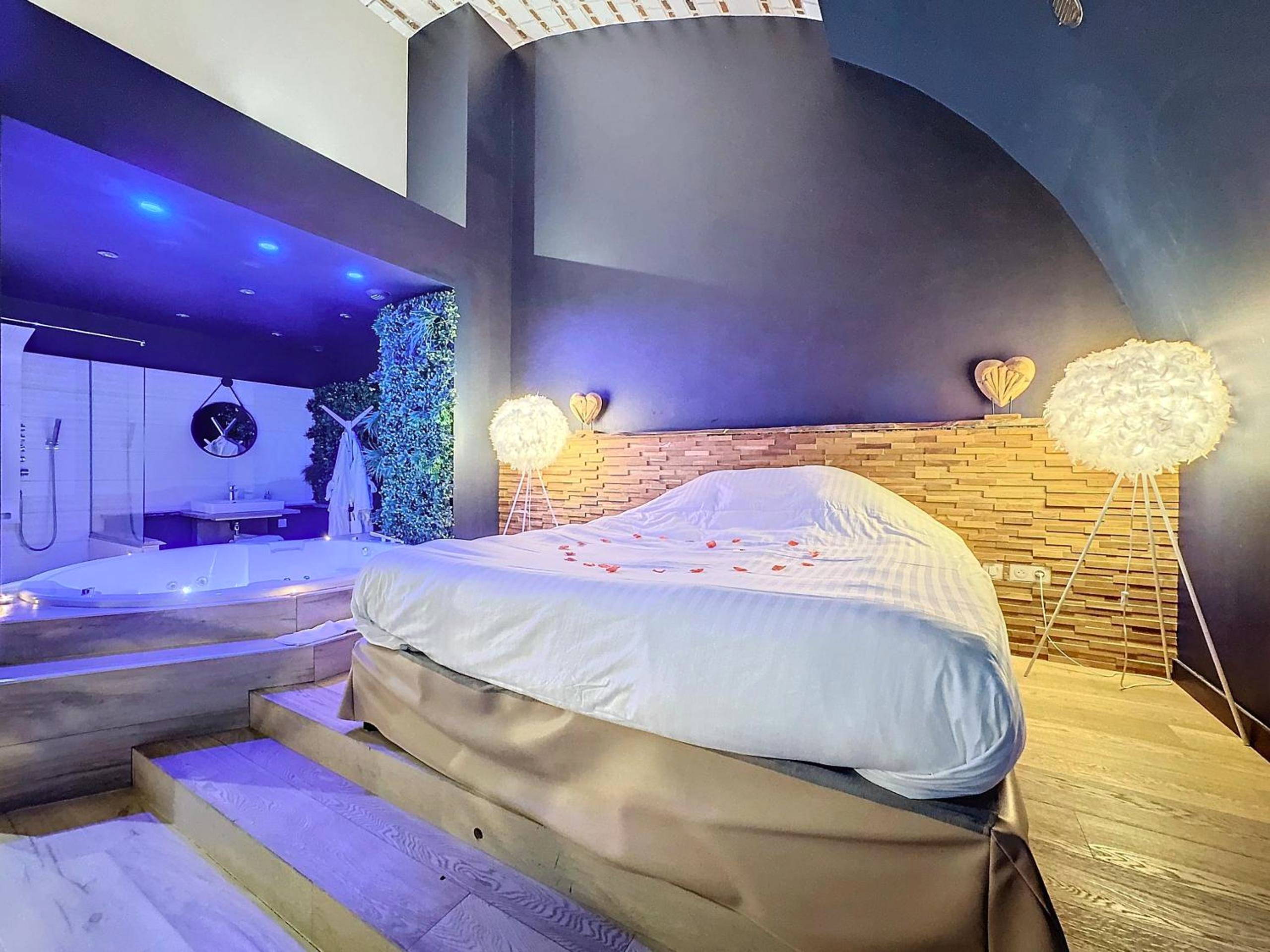 Lit king size et jacuzzi sous lumière bleue - Love Room Amiens - La Parenthèse Envoutée