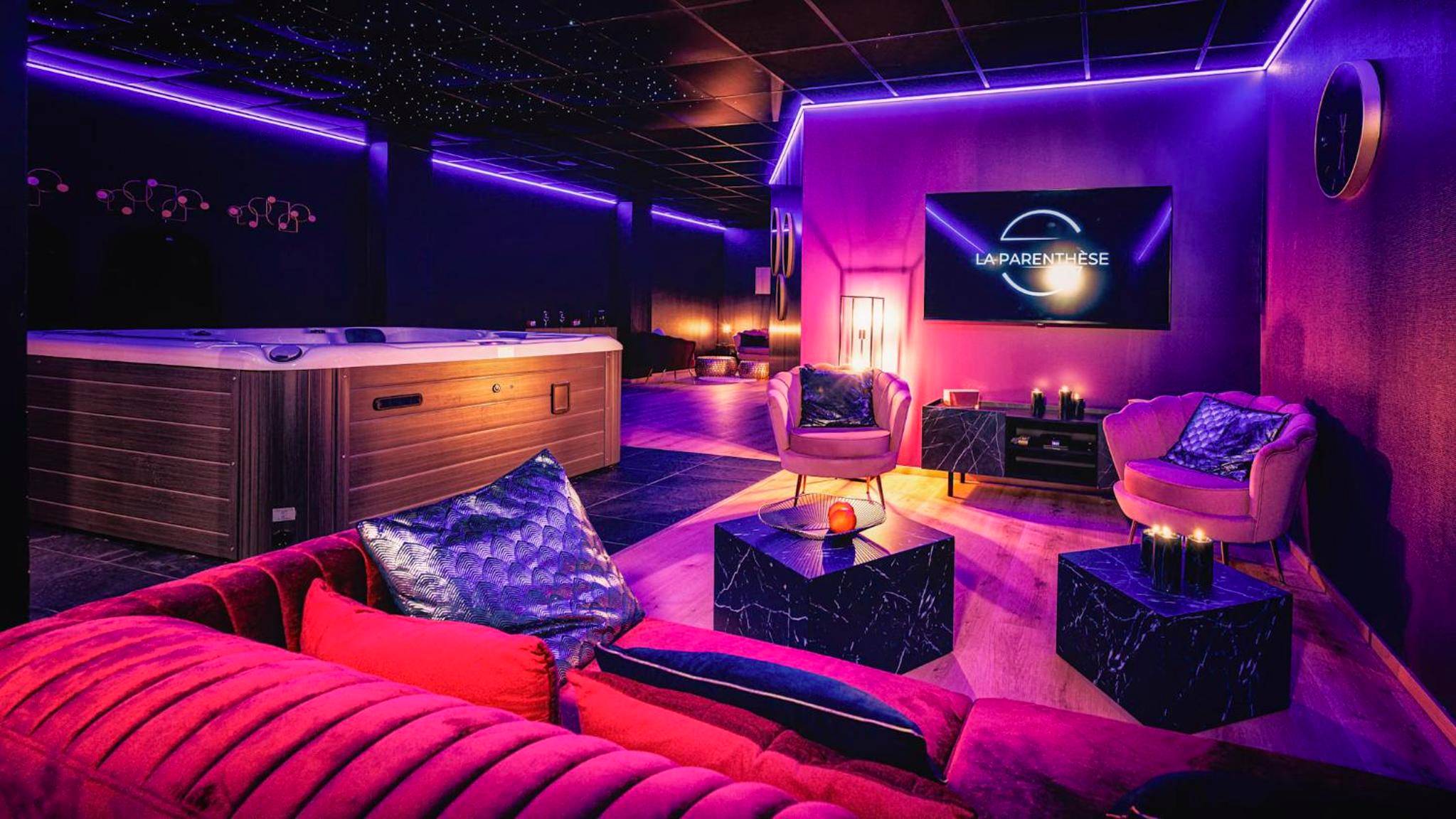 Salon avec jacuzzi et éclairage néon violet - Love Room Cognac - La Parenthèse Jacuzzi sauna privatif Cognac