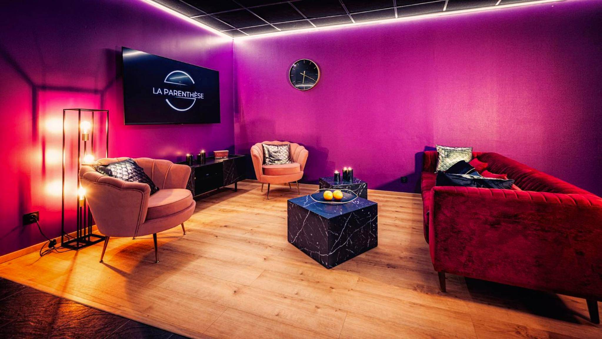 Salon design avec canapé rouge et fauteuils roses - La Parenthèse Jacuzzi sauna privatif Cognac