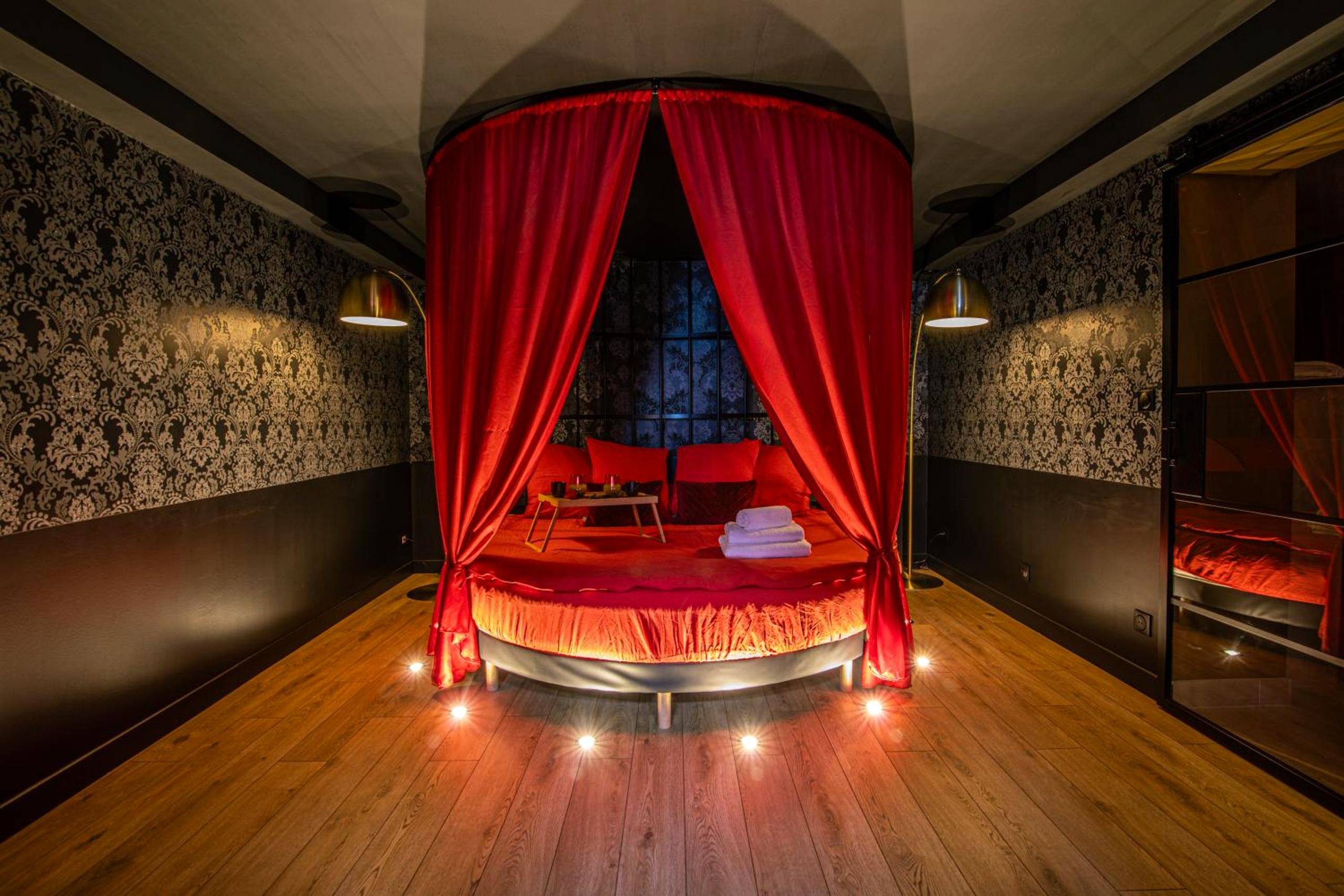 Lit rond à baldaquin rouge et bougies au sol - La Parenthèse Numéro 6 - Jacuzzi Reims
