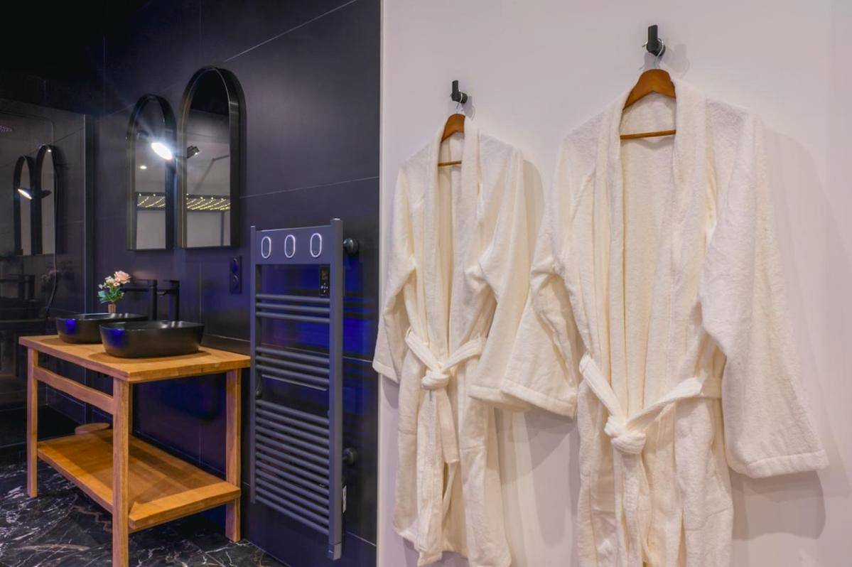 Peignoirs blancs suspendus dans la salle d'eau - La Parenthèse Sensuelle - love room