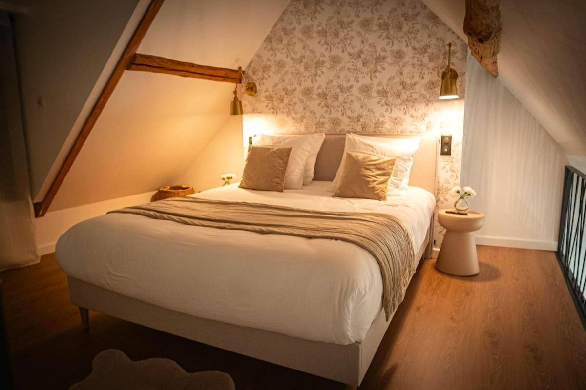 Chambre mansardée avec lit double et papier peint - La Parenthèse Suites - appartement luxueux avec sauna et baignoire balnéo