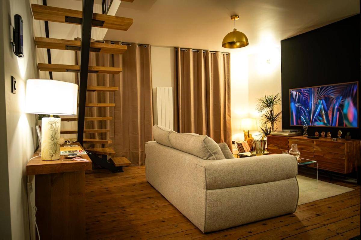 Espace séjour avec escalier bois et écran plat - La Parenthèse Suites - appartement luxueux avec sauna et baignoire balnéo