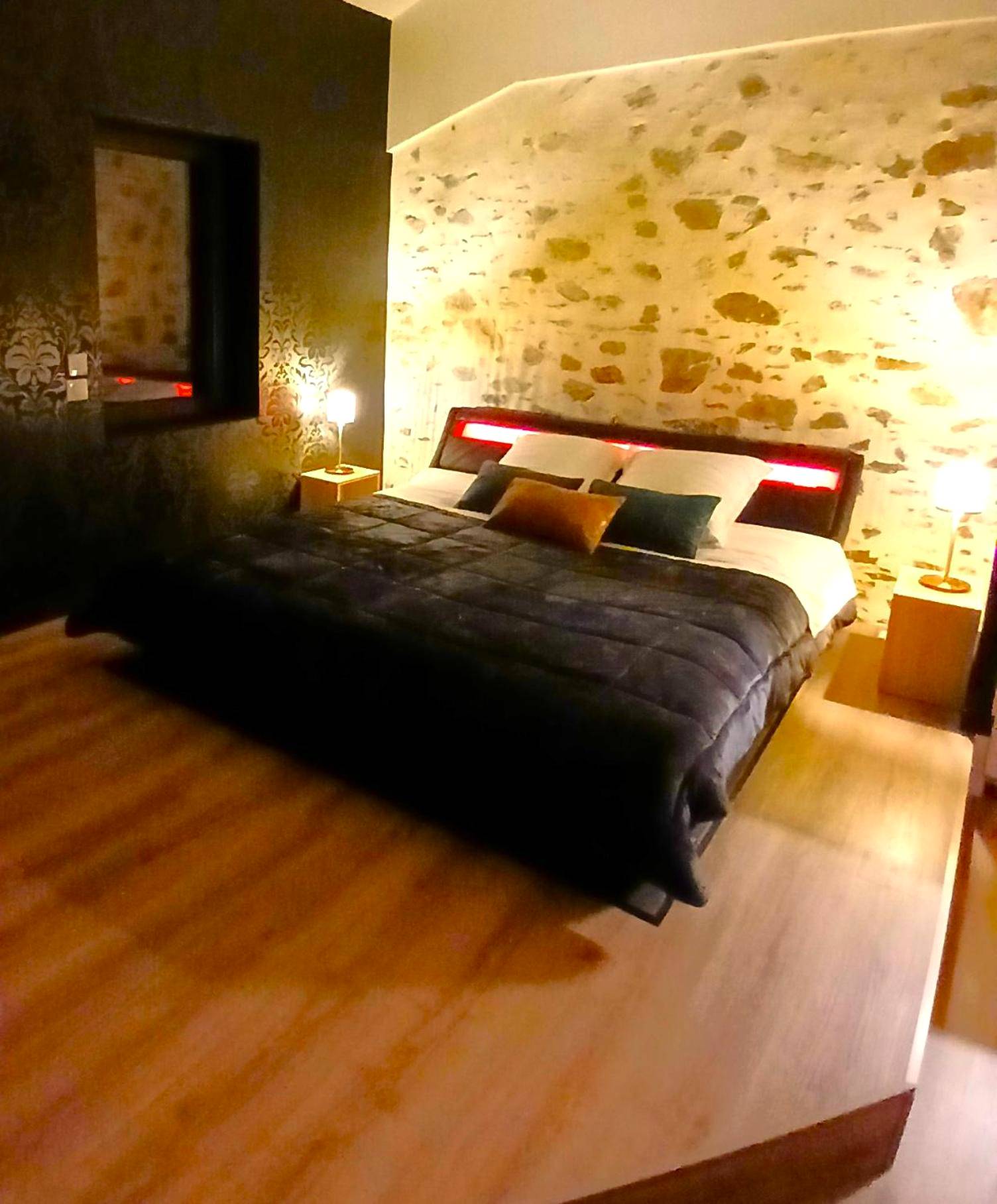 Lit double sur estrade devant mur en pierre - Love Room Saint - Philbert - de - Bouaine - La Passionnante Gîte avec Spa...