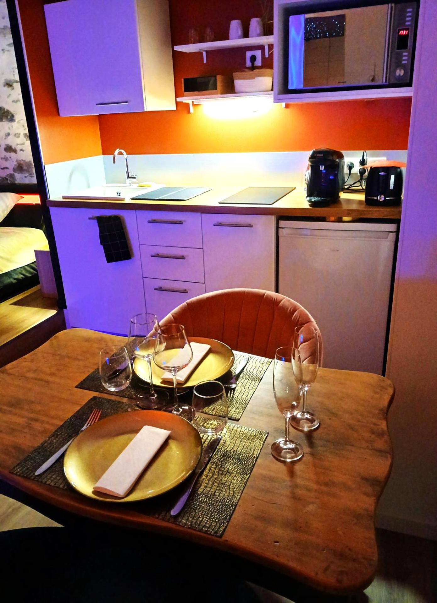 Espace repas dressé et coin cuisine équipé - La Passionnante Gîte avec Spa privatif