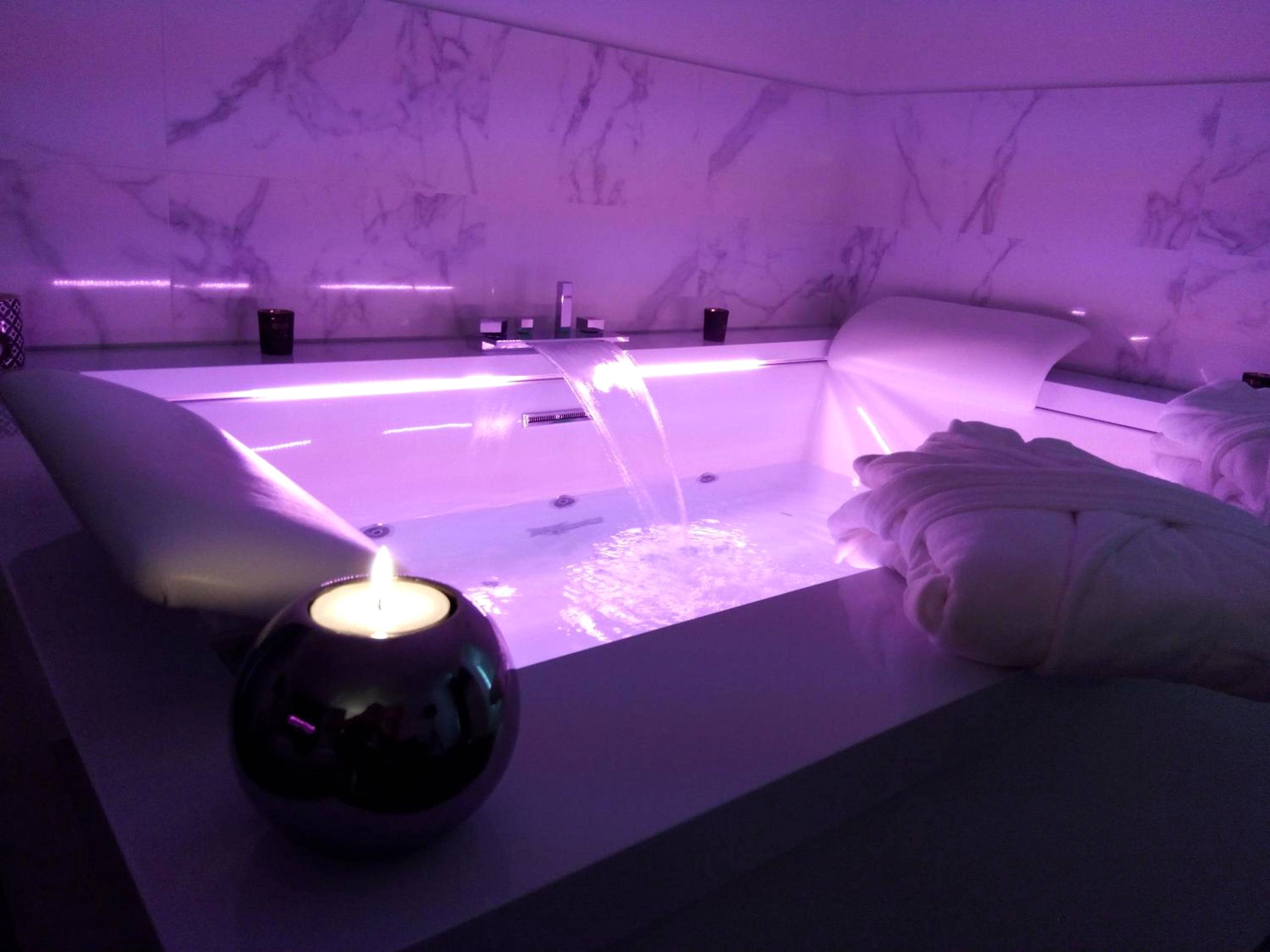 Baignoire balnéo avec éclairage rose et bougie - Love Room Dole - La Pause Romantique