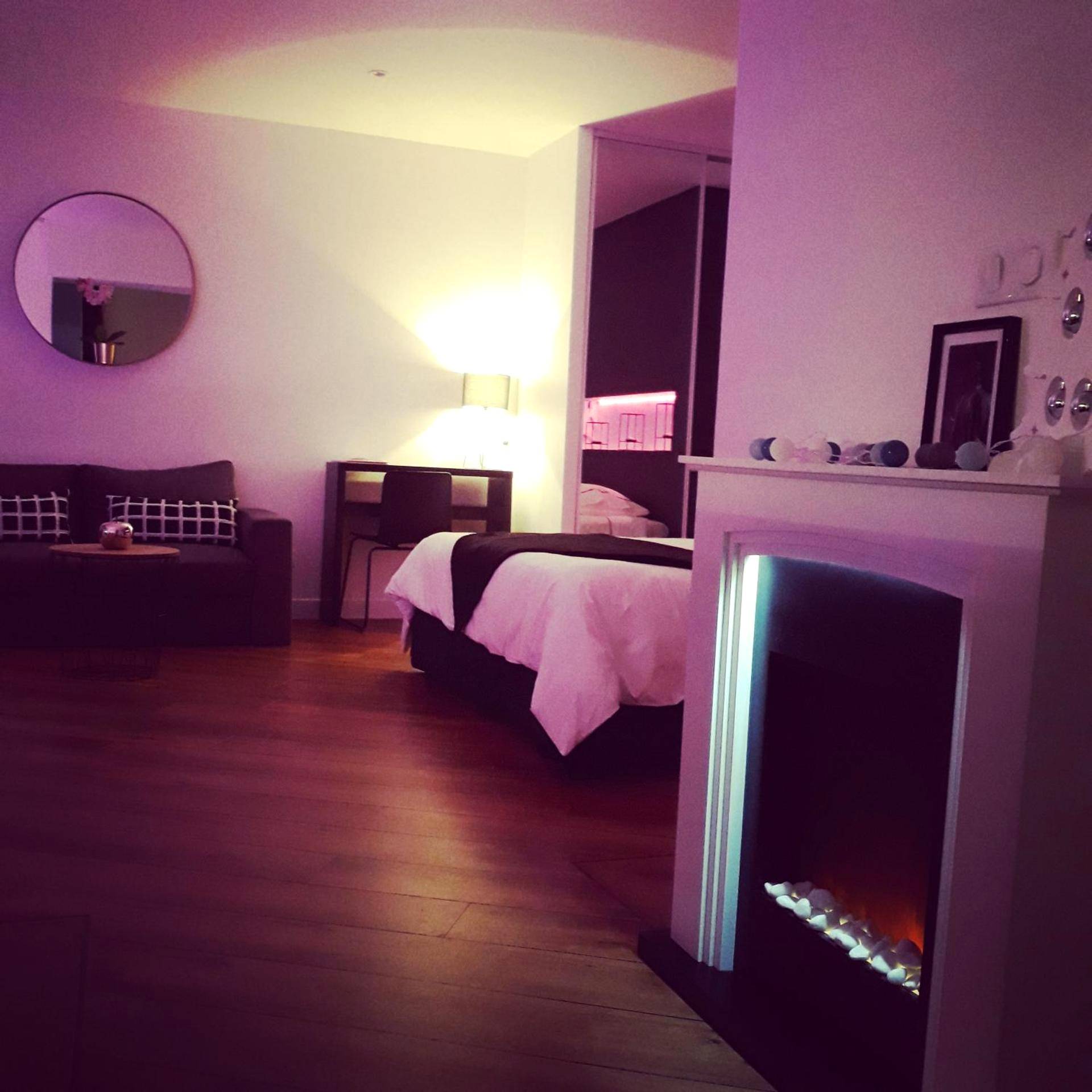 Salon avec cheminée décorative et lit en fond - La Pause Romantique