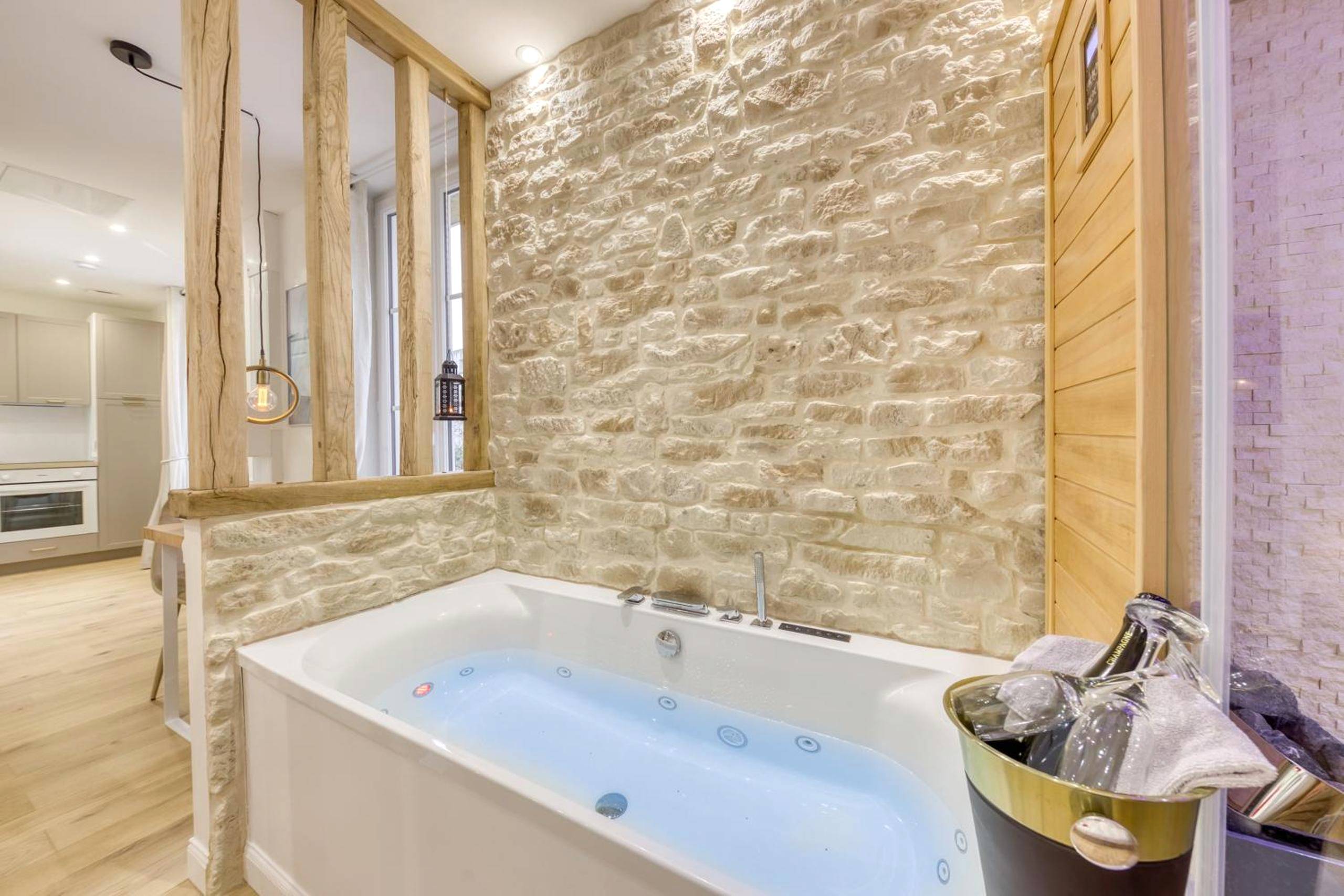 Jacuzzi privatif devant un mur en pierre - Le Petit Paris - Cocon & Spa & Sauna