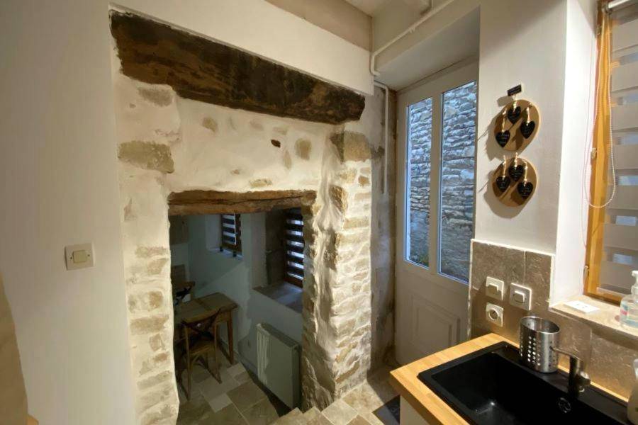 Cuisine avec évier noir et murs en pierre - Le Petit Secret d'Alban