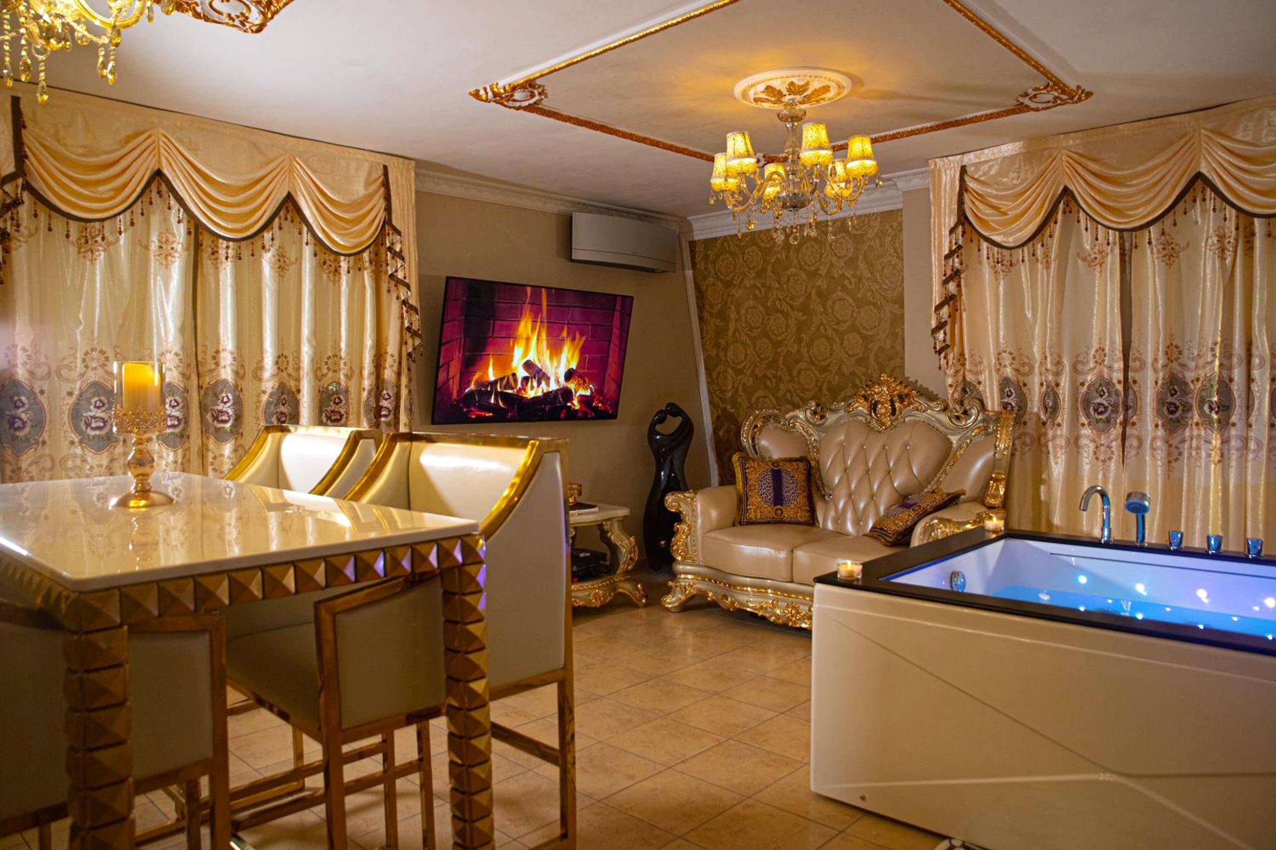 Espace salon avec jacuzzi et cheminée sur écran - Le Petit Versailles