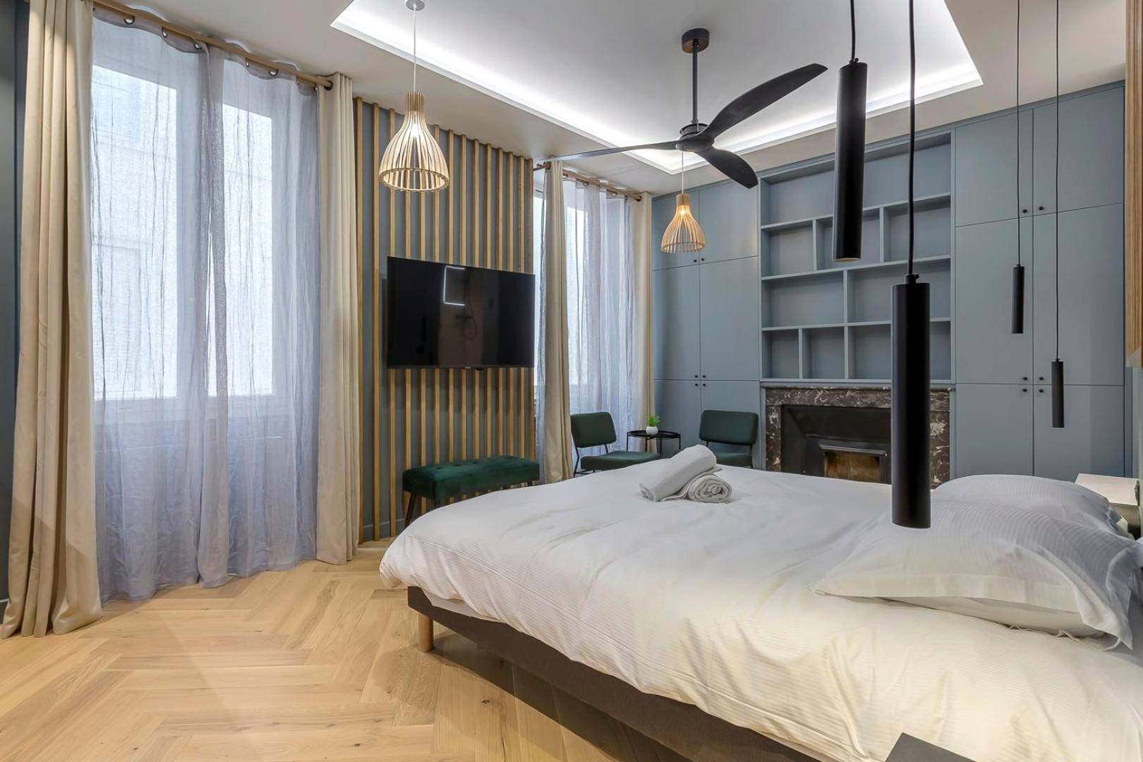 Espace nuit avec TV murale et parquet en chevrons - Love Room Balneo Sauna Pierre Corneille !