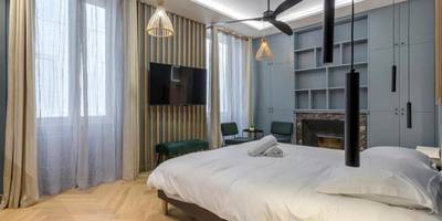 Espace nuit avec TV murale et parquet en chevrons - Love Room Balneo Sauna Pierre Corneille !