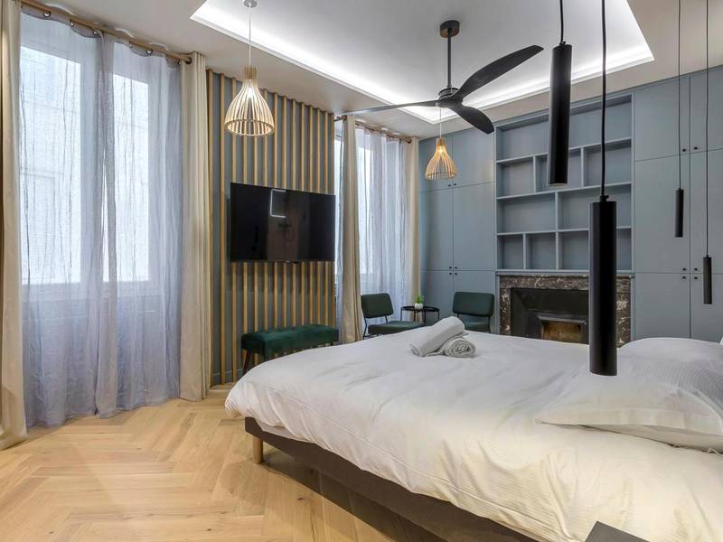 Espace nuit avec TV murale et parquet en chevrons - Love Room Balneo Sauna Pierre Corneille !
