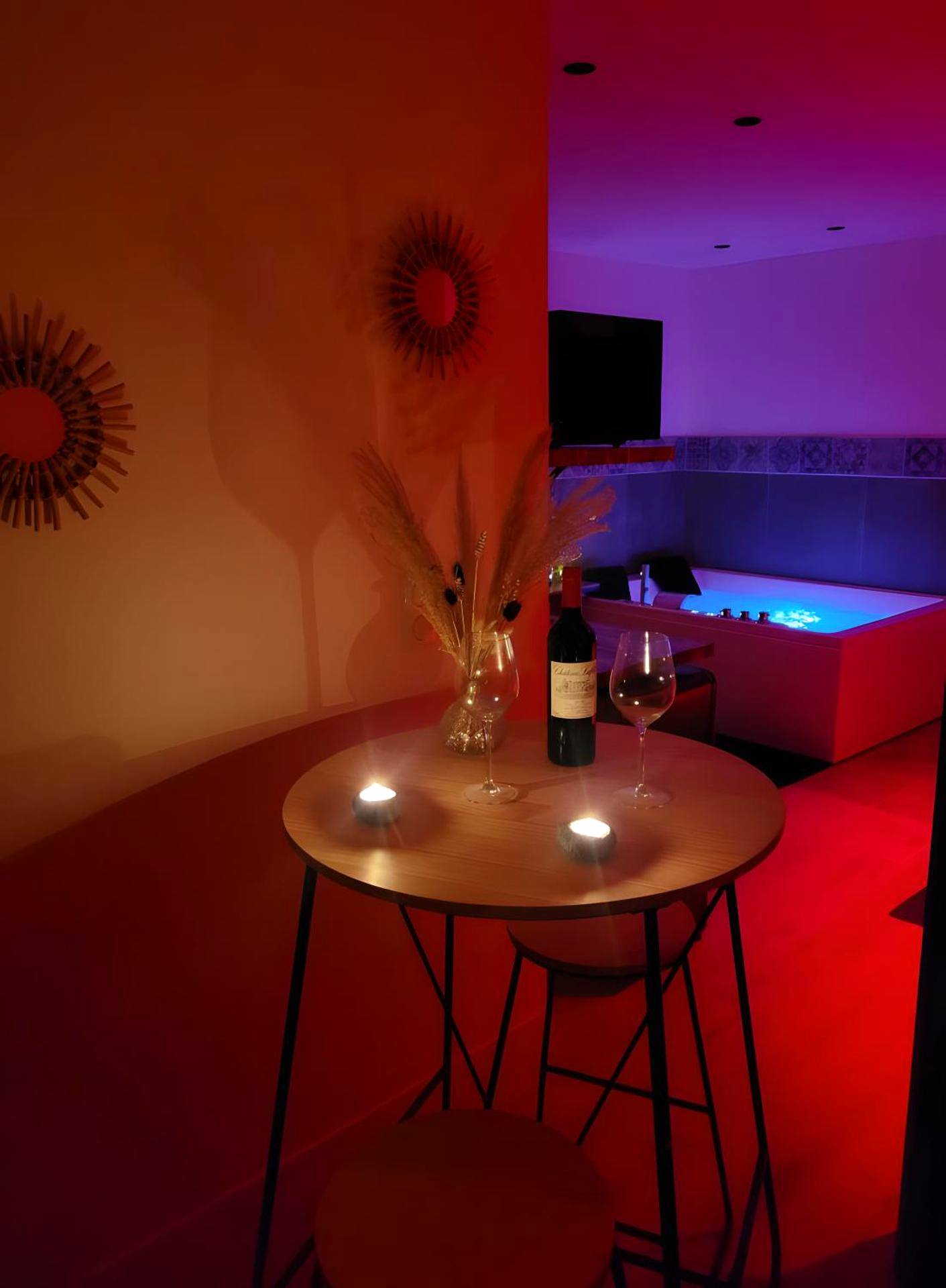 Table haute avec vin et bougies près du jacuzzi - Le Plaisir Des Sens