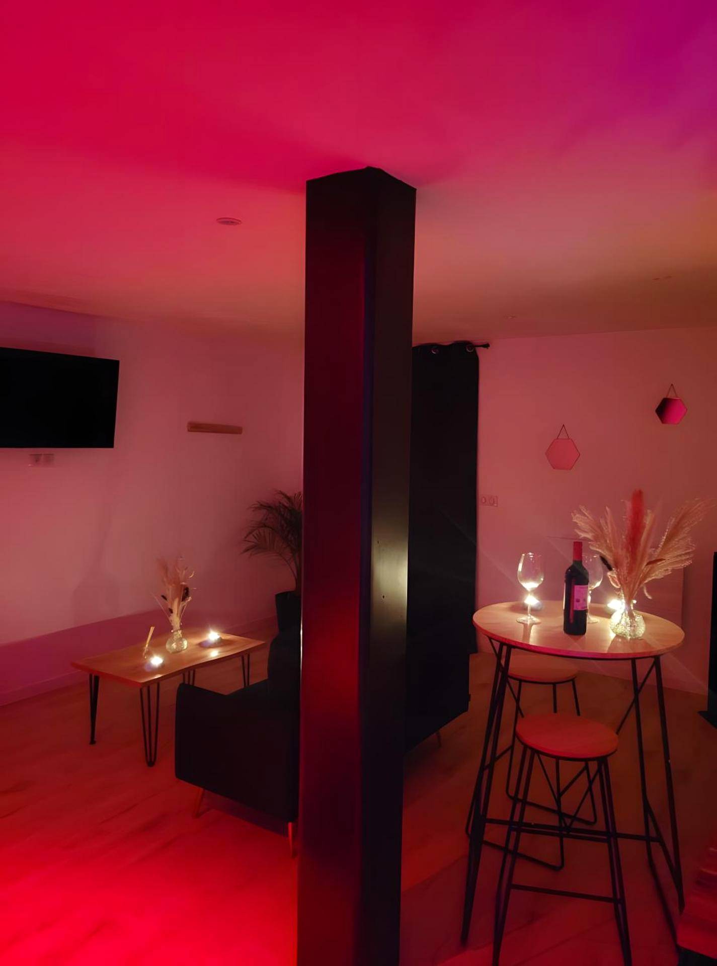 Espace salon et coin repas sous lumière rouge - Le Plaisir Des Sens