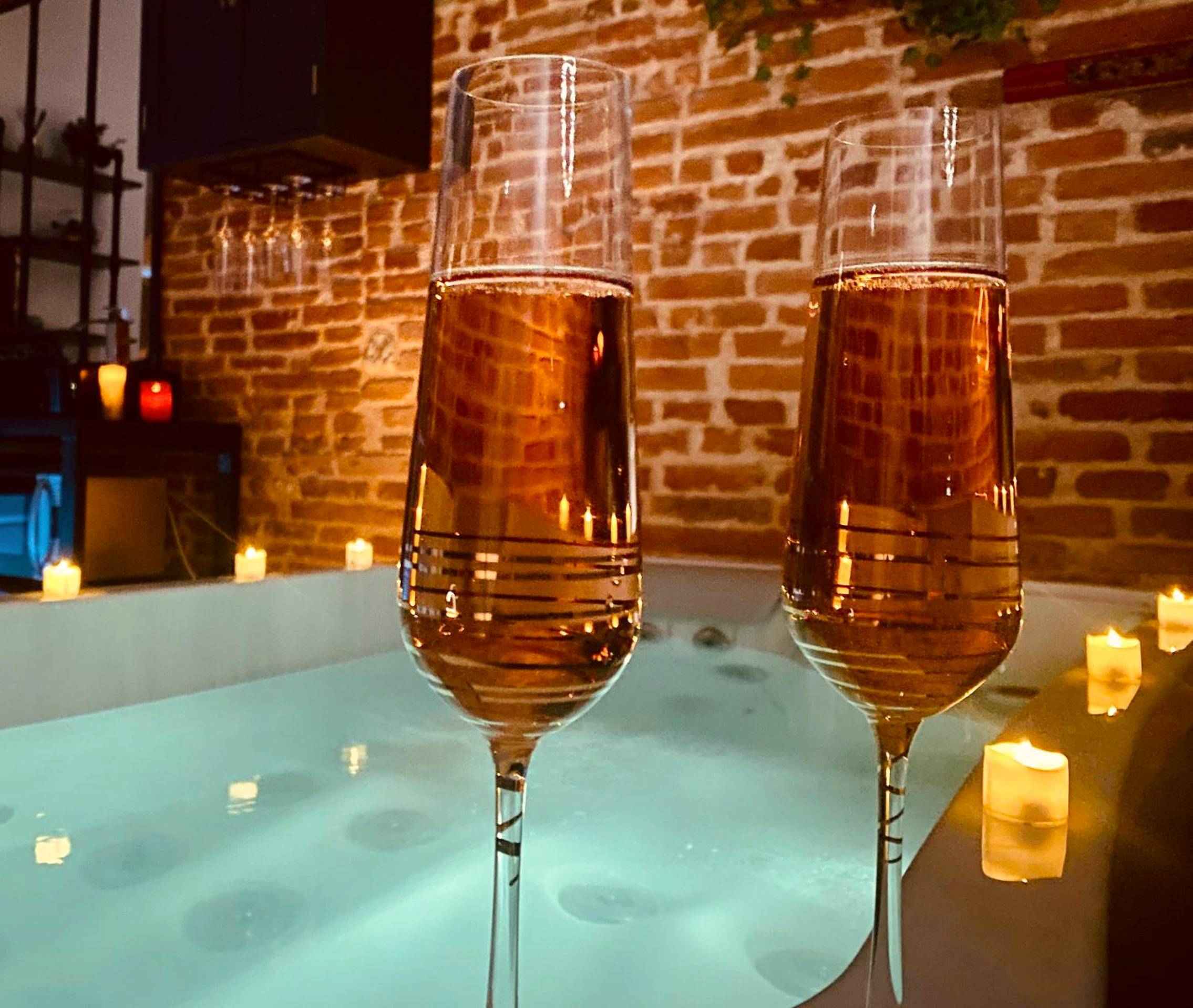 Coupes de champagne devant un jacuzzi éclairé - LE PRIEURE - Suites romantiques spa privatif, piscine, jardin, massages...