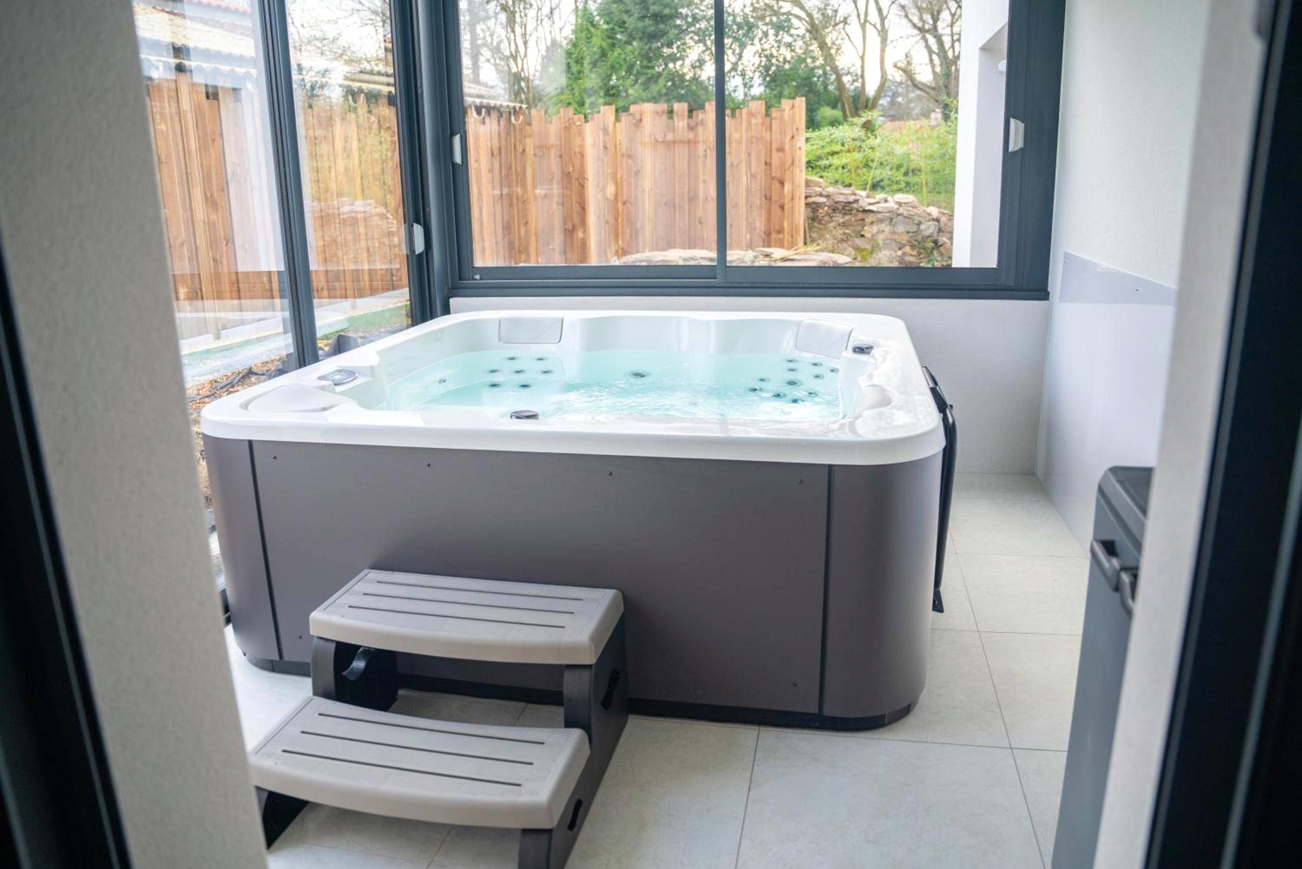 Jacuzzi privatif sous véranda avec vue jardin - Love Room Vertou - Projecteur sur ma bulle - Studio Viens dans ma bulle...