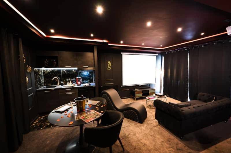 Espace salon avec écran géant et fauteuil tantra - Promesse d'une nuit avec Balnéo privative