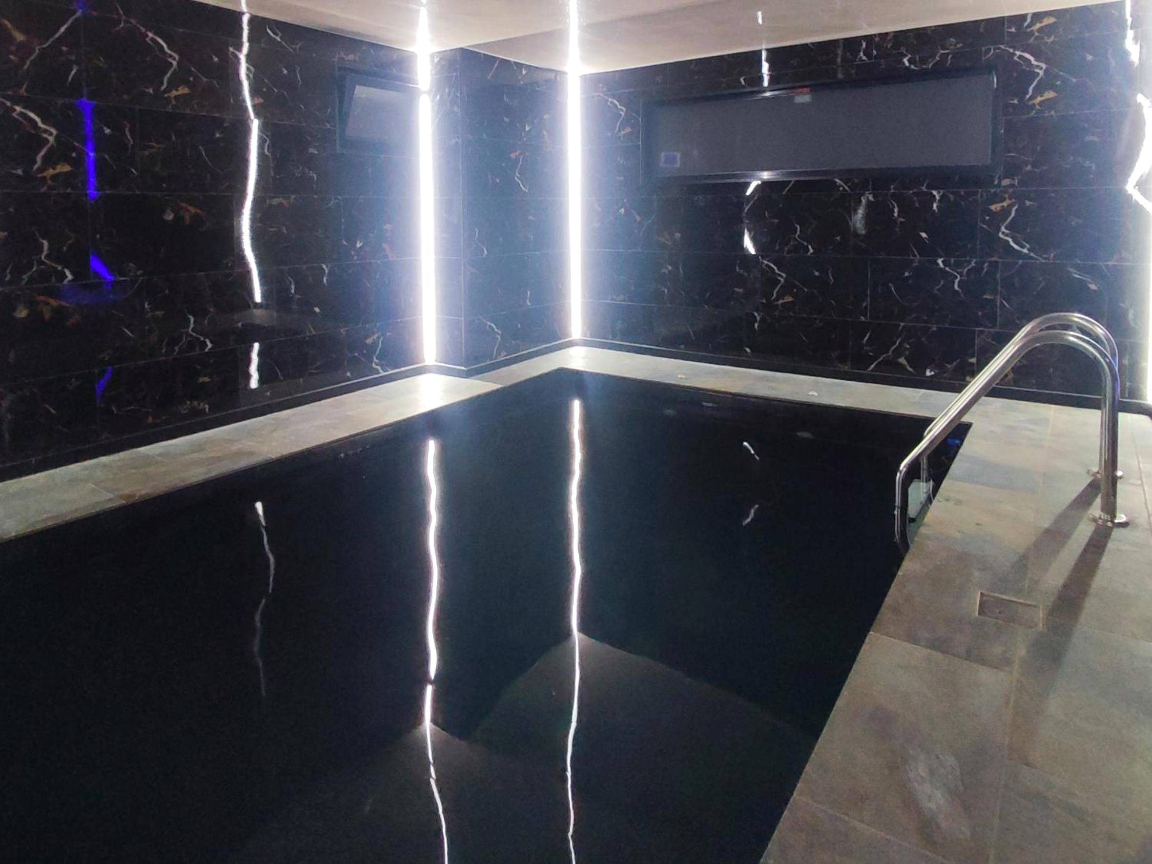 Piscine intérieure avec murs en marbre noir - Love Room Colmar - R luxury piscine et spa privatifs